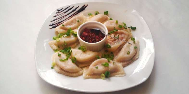 Maria Escaleira - Pierogis recheados com carne seca e requeijão, cobertos com molho e com acompanhamento de bacon