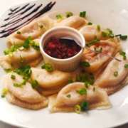 Maria Escaleira - Pierogis recheados com carne seca e requeijão, cobertos com molho e com acompanhamento de bacon - Capa