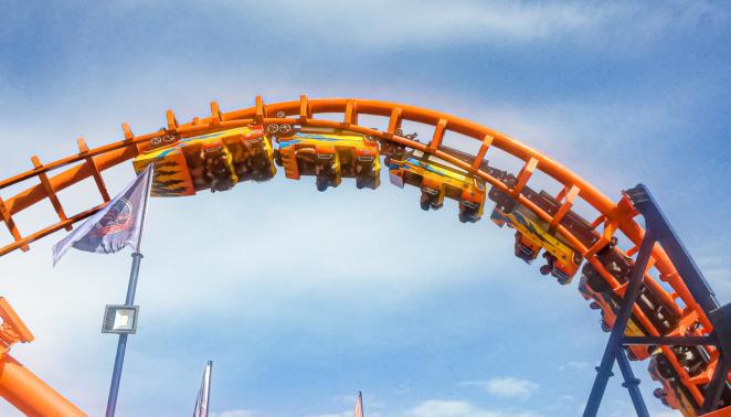 Brinquedos do Beto Carrero World - Montanha-russa Star Mountain Em frente a um céu azul, mas parcialmente nublado, um carro de montanha-russa aparece seguindo pelos trilhos de ponta-cabeça