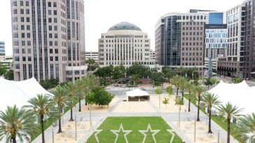 Praça com gramado e prédios ao fundo em vista do Dr. Philips Center para o centro de Orlando.